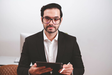 Businessman, Confident Male executive commuter is looking at hand held digital tablet screen. Confident professional making successful plan while working on laptop at office.