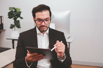 Businessman, Confident Male executive commuter is looking at hand held digital tablet screen. Confident professional making successful plan while working on laptop at office.