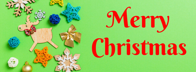 Fototapeta na wymiar Merry Christmas text. Top view Banner of green background with New Year toys and decorations. Christmas time concept with copy space
