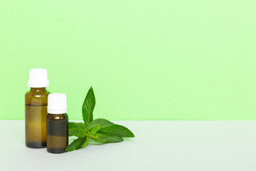 Natural Mint Essential Oil in a Glass Bottle. organic cosmetics with herbal extracts of mint on colored background