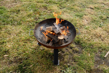 A fire pit on a farm lit with a small fire and eco recycled wood  you can see flames and smoke