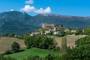 Fototapeta na wymiar Vue distante du vieux village de Mison, France, entouré de collines, au pied de son château médiéval, situé dans le département français des Alpes-de-Haute-Provence