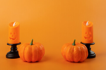 halloween decoration, orange pumpkins and halloween candle on orange background