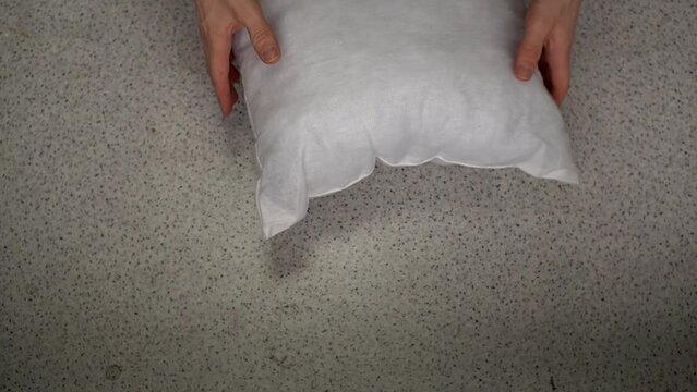 man testing a white pillow for elasticity