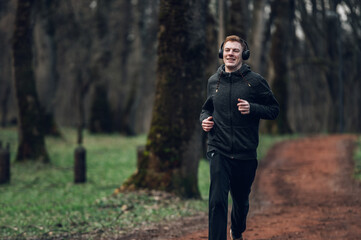 Young redhead man running in forest