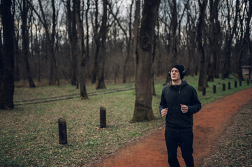 Young redhead man running in forest