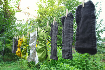 Reusable diapers are dried on clothesline outside in garden. Modern eco friendly cloth nappy for...