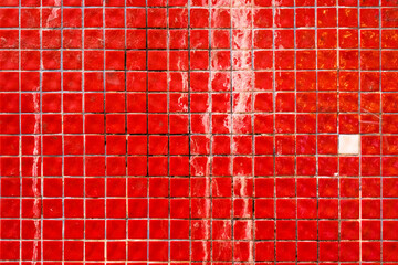 Small red dirty ceramic tiles on the building facade, retro mosaic wall surface, grunge texture and pattern, background.