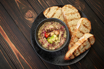 Hummus on a black plate on a wooden background