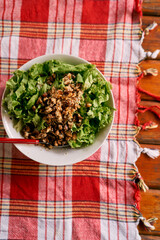 Lettuce salad with chicken meat in a plate stands on a checkered tablecloth. High quality photo
