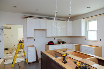 In a set of furniture under construction, white kitchen wooden cabinets were installed with a home...
