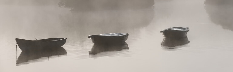 Fishing boats in lake and early morning mist with boats in background