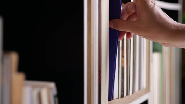 Finding book concept. Hand finding book on bookshelf, to reading and learning the new knowledge to improve the skill for their work.