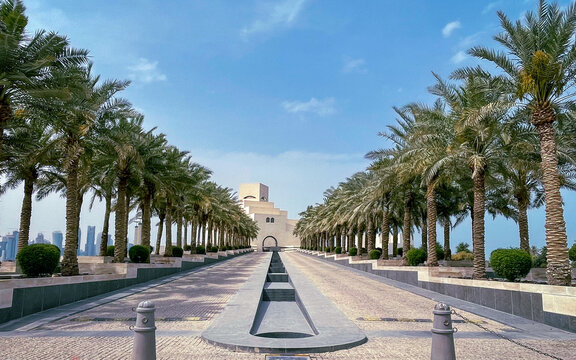 Avenue entrance to the famous Museum of Islamic Art -perspective with palm trees on both sides and a channel fountain with running water in the middle in Doha, Qatar, Persian Gulf on Apr 13, 2022.