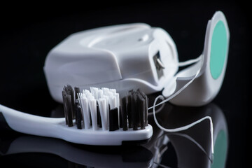 Close up of toothbrush and dental floss on black