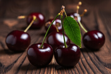 Sweet cherries with cherry leaf on a wooden background.