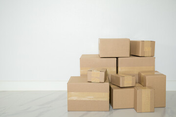 Stack of cardboard boxes for moving, Empty room with a white wall and cardboard boxes with unbranded barcode on the floor. Delivery of goods, shopping. Cardboard boxes on gray wall background.