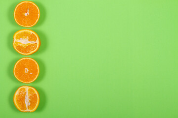 Top view of orange fruit slices on bright background in green color. Saturated citrus texture image