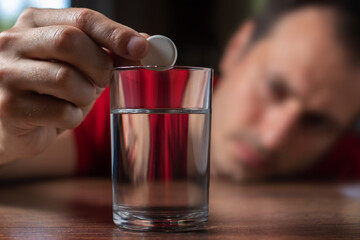 Man taking medicine for hangover at home, focus on hand with pill