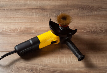 Electric tool; yellow grinder with iron brush on a wooden background