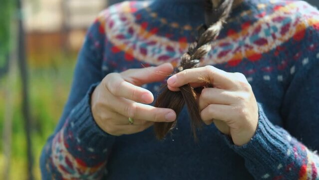 close-up of a woman in a jacket braiding a braid