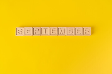 September word on wooden blocks. Yellow background