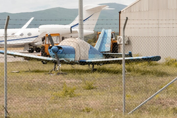 An old propeller plane is at the airfield. An old broken-down blue propeller plane abandoned for...