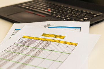 Close up shot of a print outs of excel table of a bank loan amortization table, personal balance sheet and laptop. Banking