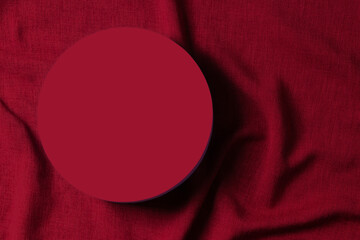 Blank round platform podium for cosmetics or products on red color linen fabric background. Top...