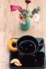 Rosquinhas na mesa com outros doces, jarro de flores e café