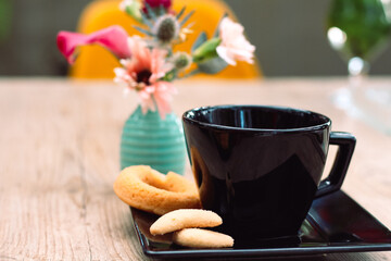 Rosquinhas na mesa com outros doces, jarro de flores e café