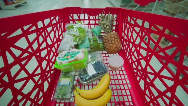 Close-up video of timelapse of shopping the supermarket view of a shopping red trolley cart with food. Inflation. Consumer basket. Crisis. Decrease in purchasing power
