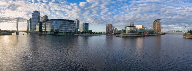 Panoramic view of several buildings in the city of Manchester, reflected in the calm waters of the...
