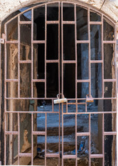 A photo of an old ruin demolished building with rusty iron railing and a metal lock on the door
