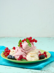 Vanilla ice cream balls with red raspberries in a round plate.