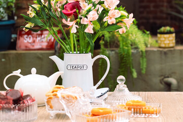 Mesa de café da manha com chá, flores e doces