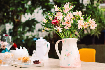 Mesa de café da manha com chá, flores e doces