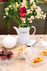 Mesa de café da manha com chá, flores e doces