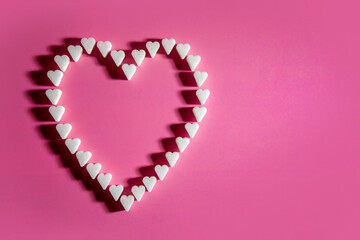 Heart made of sugar cube hearts on pink background