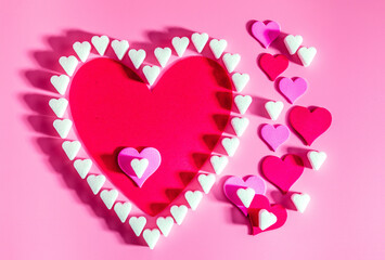 Sugar hearts and other hearts on a pink background with copy space, concept of love and romance