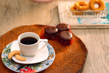 Mesa com xicara de café apoiada em pirex no suporte de madeira redondo com sequilhos