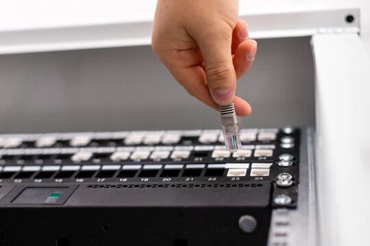 IT consultant connects network cable into switch in datacenter.