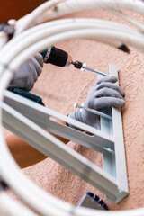 Close up of male worker installing wall mount for outdoor air conditioner unit.