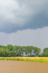 Heavy rain storm clouds wind waves water Oste river Germany.