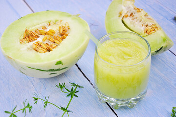 Fresh melon smoothie in the glass on the wooden table