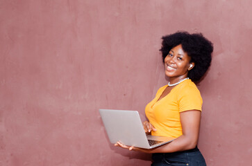 Young smiling black African woman standing with laptop computer isolated on brown background