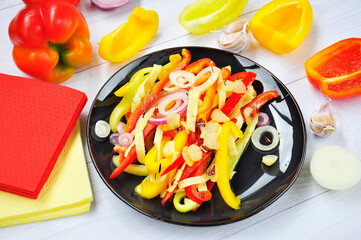 Salad of sweet bell peppers on a black plate.