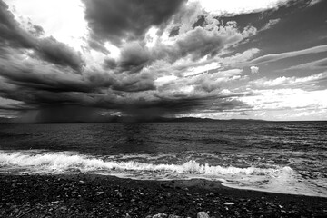Calabrian sea and the Apulian coast on the horizon, impetuous sea and very cloudy sky. Black and white photo.