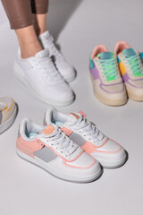 Close up of stylish white and pink women's sneakers on background of other sports shoes.