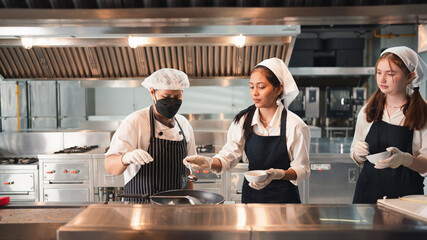 Chef in the kitchen provides cooking training to students.Schoolgirls happily cook together.children wearing cooking uniform.